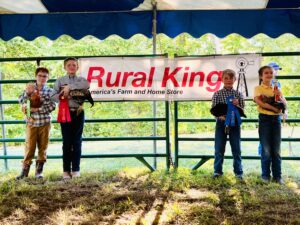 Four youths pose in front of a "Rural King" sign.