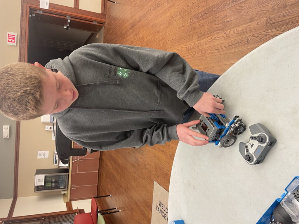 A kid in a 4-H Hoodie configures a robot.